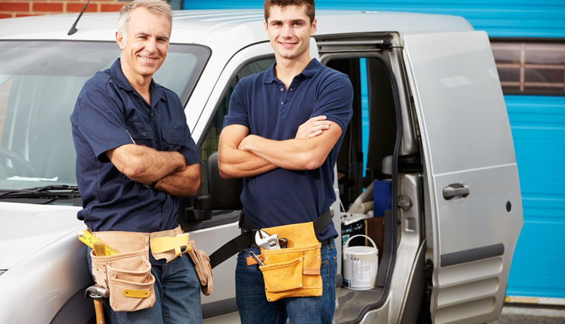 Two men smiling in front of a commercial service vehicle.
